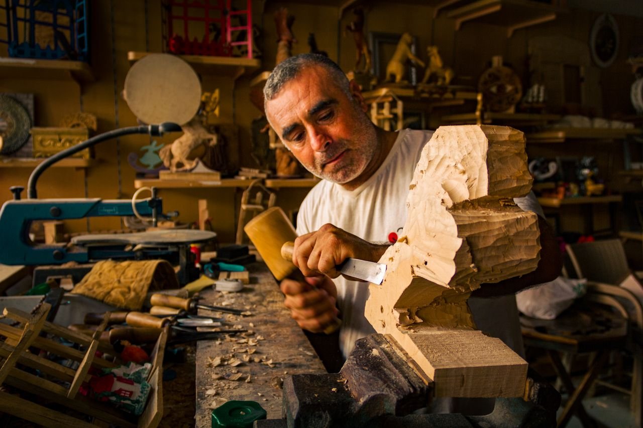 Artisan crafting a wooden sculpture in a well-equipped workshop, showcasing expert woodworking skills.